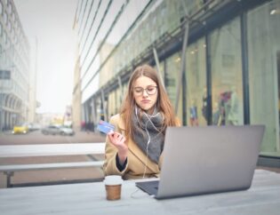 sad woman holding credit card while using laptop